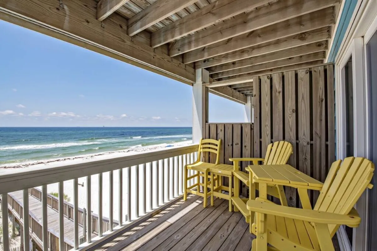 A serene balcony scene featuring cheerful yellow chairs overlooking the ocean, with a wooden railing and endless water views. The peaceful atmosphere is ideal for enjoying a morning coffee or watching the sunset.